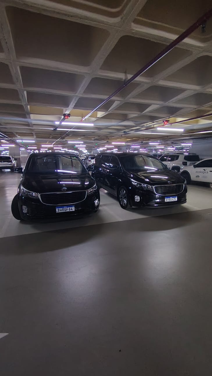 Duas minivans Kia Carnival pretas lado a lado na garagem